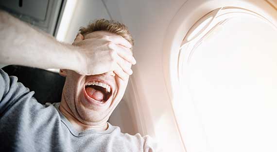 MAN COVERS EYES ON AIRPLANE