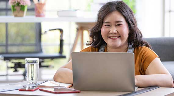 WOMAN SMILING AT DESK WITH LAPTOP