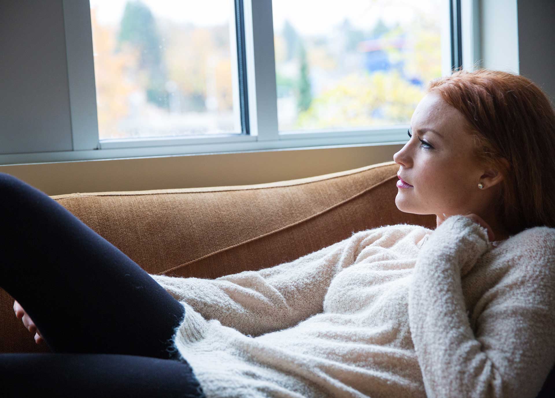 YOUNG WOMAN RELAXING BY WINDOW