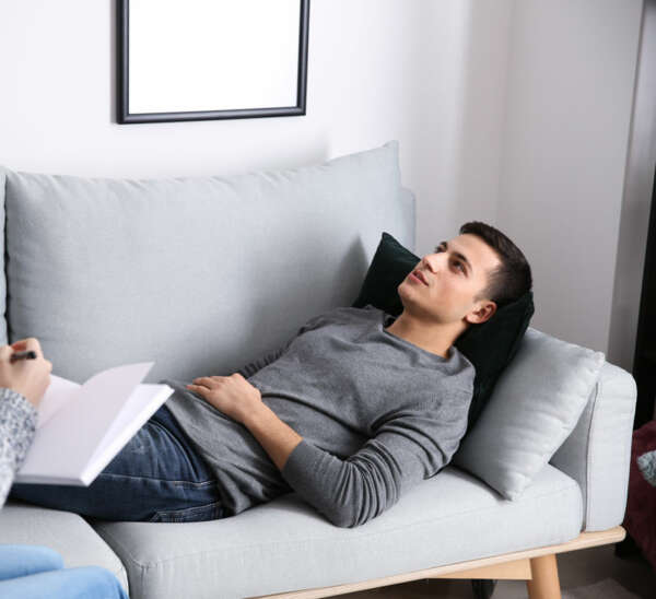 FEMALE THERAPIST WORKING WITH MALE CLIENT WHO IS RELAXING ON A SOFA